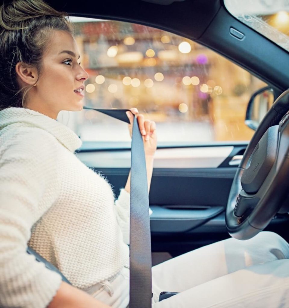 Car safety features: Young girl is fastening her seat belt.