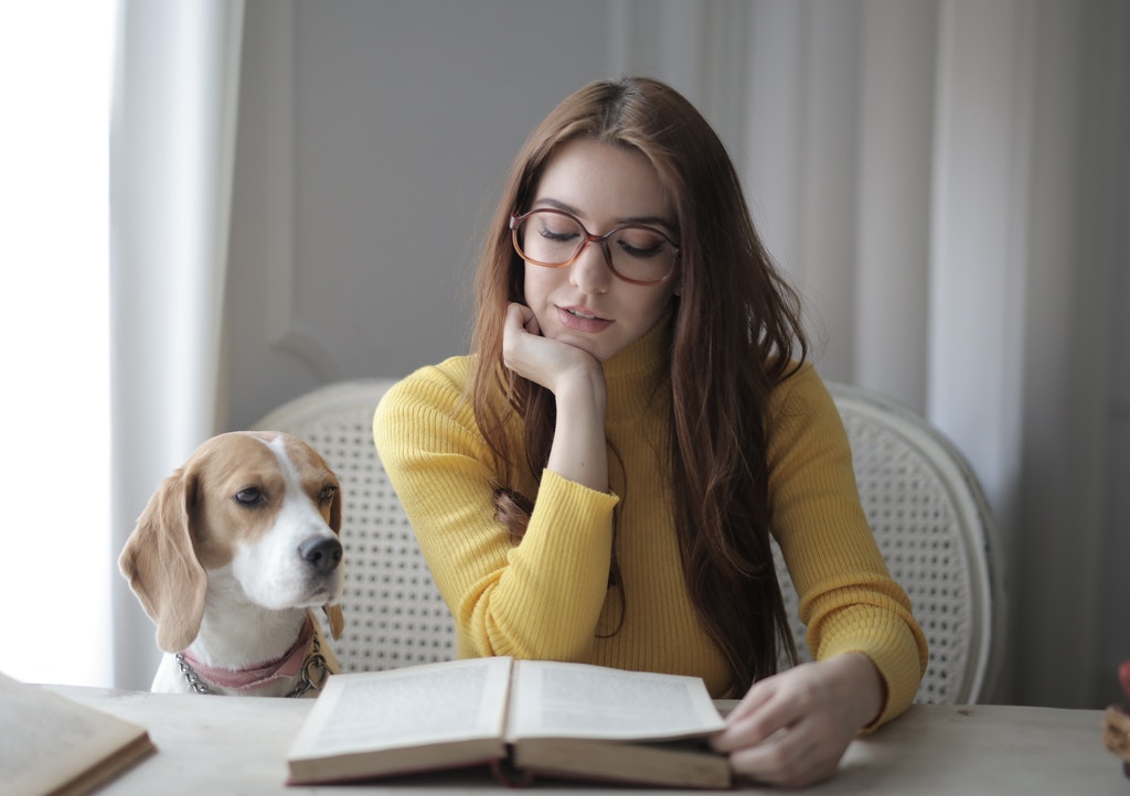 Woman Reading a Book and a Dog Sitting Next to Her. Education, Reading, Studying, Educational Support.