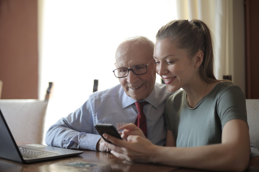 Young lady showing photos on smartphone to senior man
