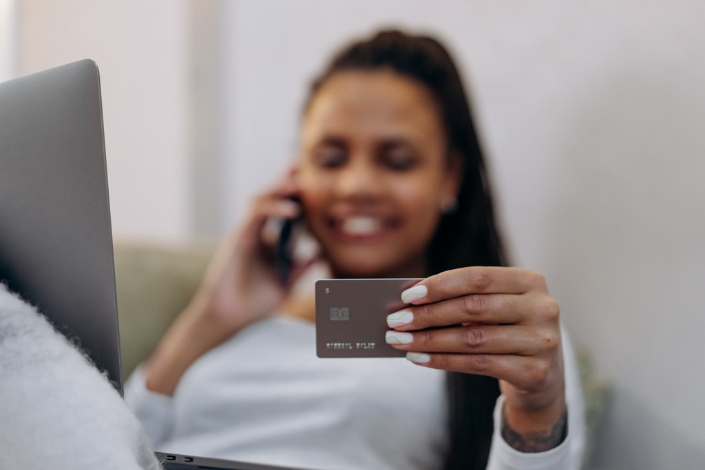 Woman Holding Brown Credit Card While Talking on the Phone