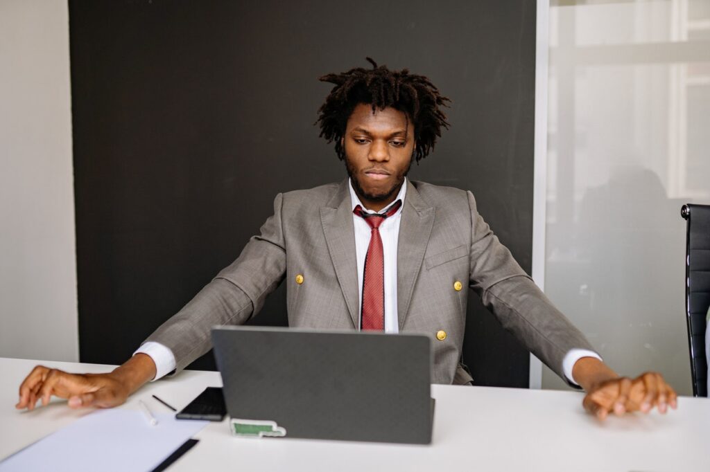 A Businessman in a Gray Suit and Red Necktie Looking at a Laptop