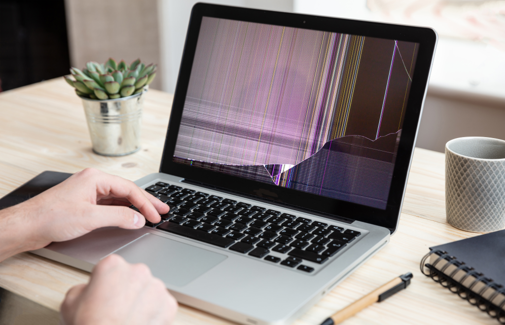 Man working with a broken laptop computer on office business background. Man working with a laptop computer with damaged screen.