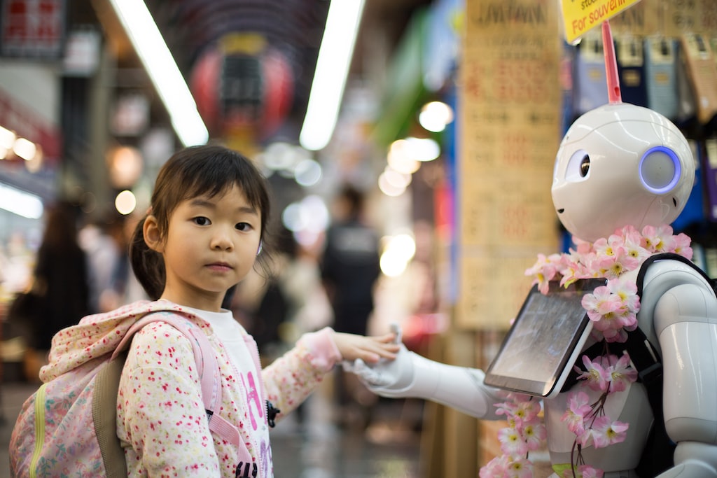 Girl laying left hand on white Artificial Intelligence Robot photo