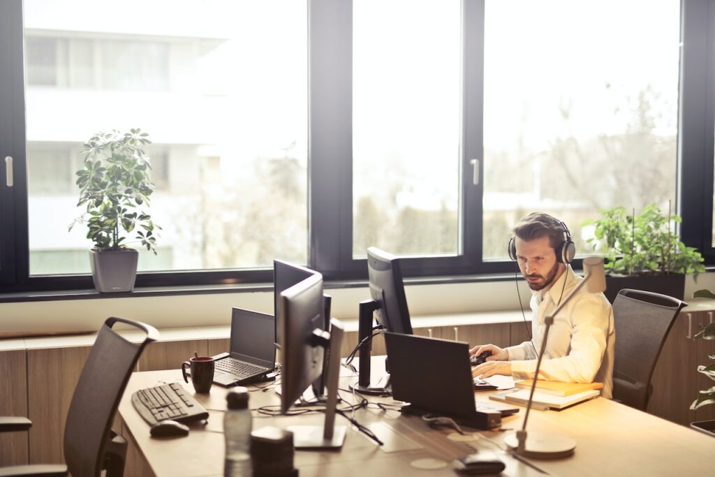 Voice Broadcast Service, Man with Headphones Facing Computer Monitor.