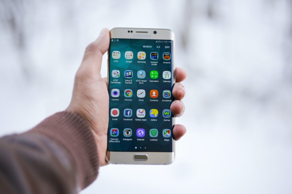 Person holding silver Samsung smartphone showing mobile apps