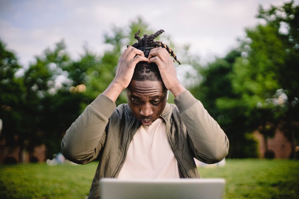 stressed male entrepreneur working on laptop in park