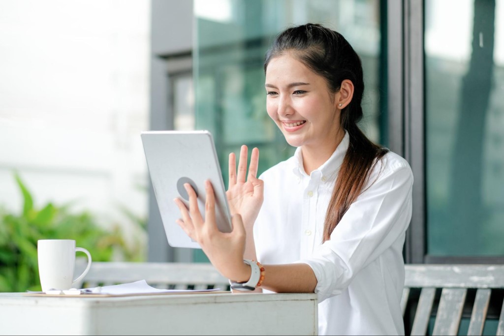 Beautiful girl waving hand to tablet for meeting and work