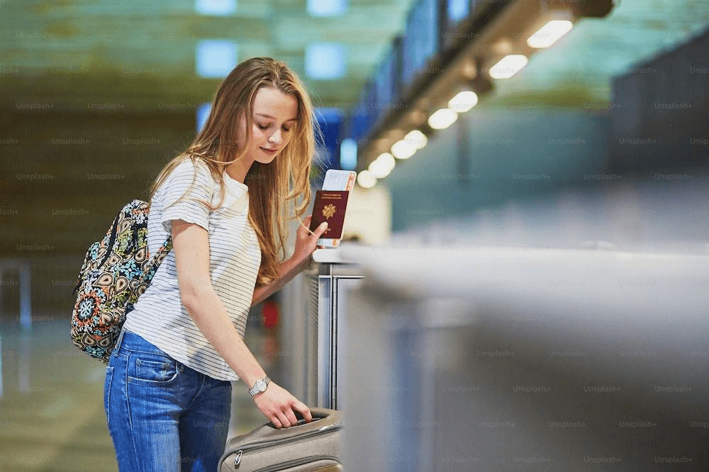 girl with luggage and passport in international airport at check-in counter