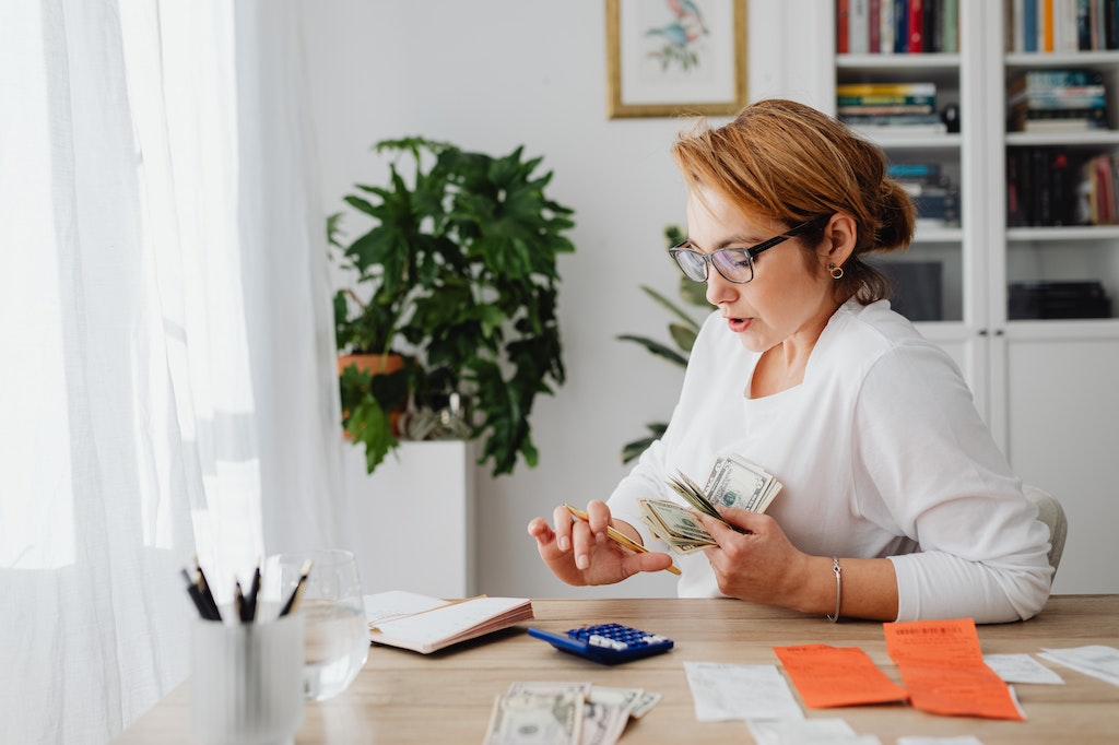 Woman Sitting at Desk Counting Money, Financial Planning, Personal Finance Management.