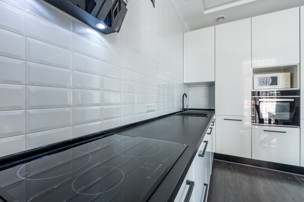 Modern Kitchen Renovation, White kitchen with black counter and built in appliances, 