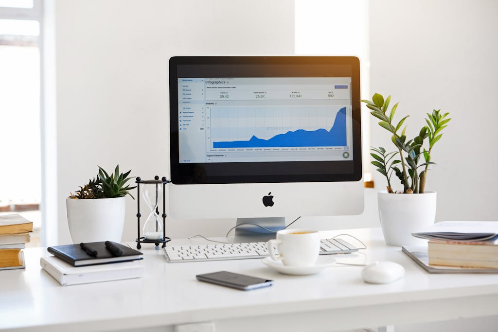 Silver iMac Displaying Line Graph Placed on Desk.
