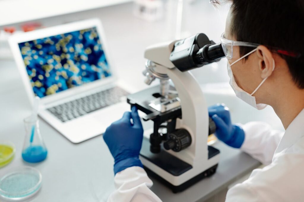 Clinical research scientist using a microscope.